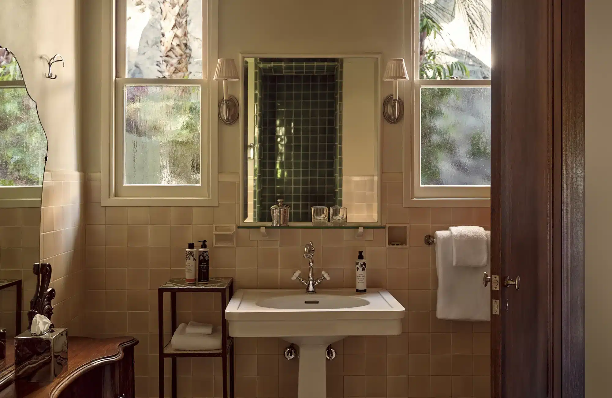 Library bathroom with two windows, sink, bath products, towels, and mirror