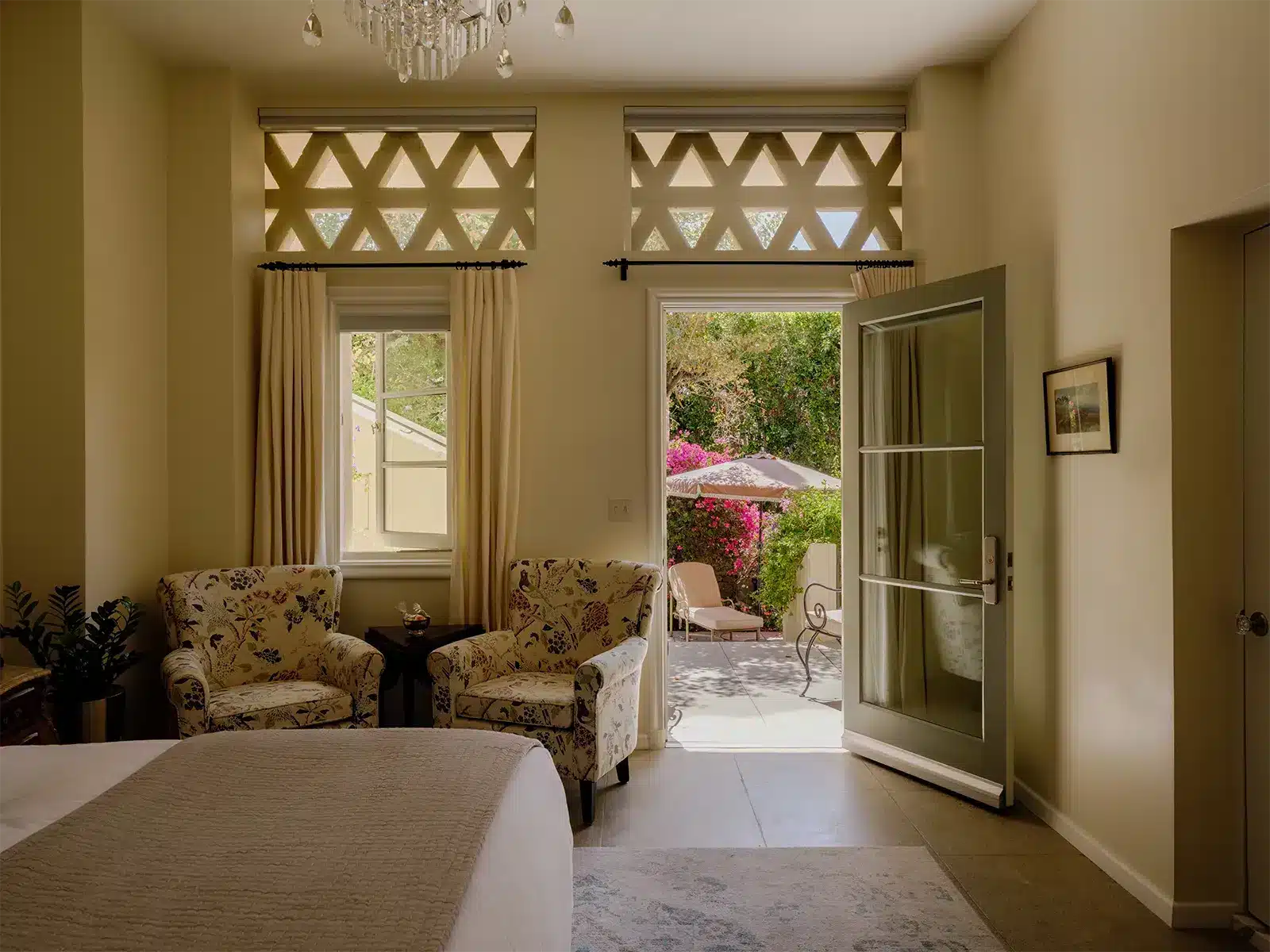 Bedroom with bed, two sitting chairs, with door open to the patio