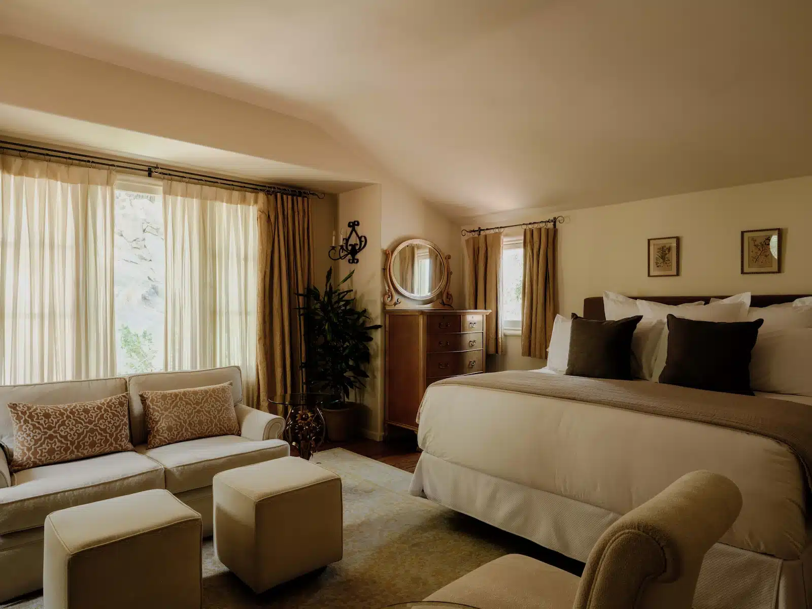 Waterfall sitting area with two chairs, couch, tables, and bed